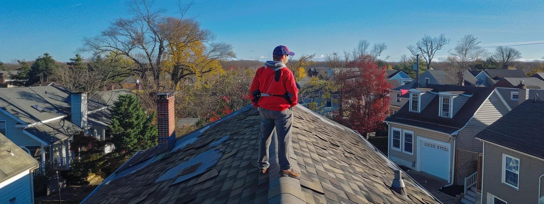 a professional home inspector examines a roof with a high-tech drone in a suburban norristown neighborhood, highlighting the importance of timely inspections to prevent costly repairs with a clear, bright sky in the background.